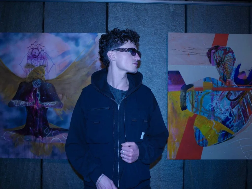 Marlon Nikolai in front of two works