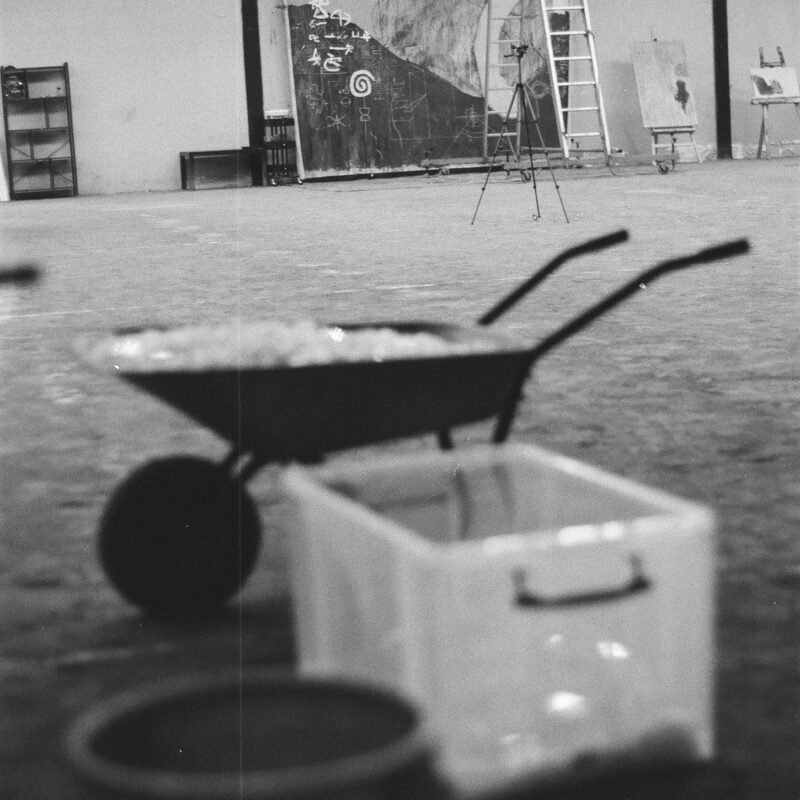 Black-and-white analog photograph of Marlon Nikolai’s studio, showing a glass work, ladder and work in progress.